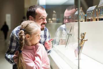 Father and daughter looking at religious art in museum
