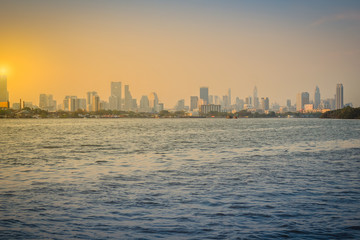 Fototapeta premium Chao Phraya river during sunset with high-rise condominium in blue and yellow sky background. Riverfront view of real estate development, Bangkok, Thailand.