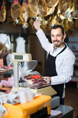 male seller weighing piece of meat in butcher’s shop