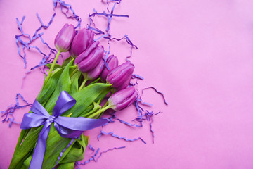 violet tulips on pink background festive bouquet for birthday, March 8, baby shower, mother's day, women's day. floristic composition. festive confetti. with purple ribbon
