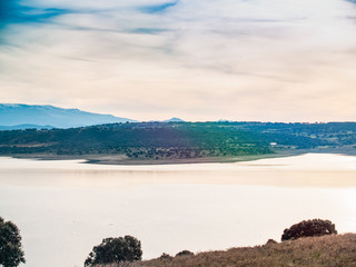 Landscape of a reservoir and mountains in a day with fog and clouds and birds swimming and flying in in La Maya Reservoir (Salamanca)