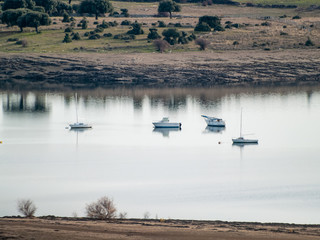 Boats on a lake at sunset, moored with a buoy and calm water in the reservoir of La Maya (Salamanca)