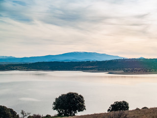 Landscape of a reservoir and mountains in a day with fog and clouds and birds swimming and flying in in La Maya Reservoir (Salamanca)