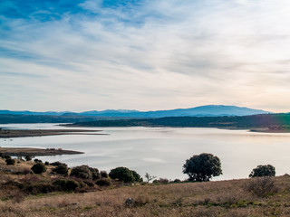 Landscape of a reservoir and mountains in a day with fog and clouds and birds swimming and flying in in La Maya Reservoir (Salamanca)