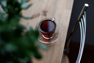 Black tea or coffee in a glass cup on wooden table