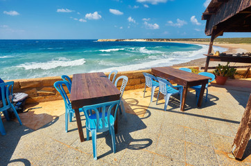 Tables and chairs in a cafe with palm trees on the beach Lara