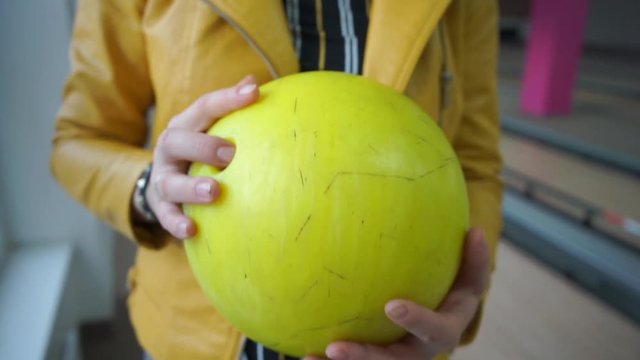 girl holds a yellow bowling ball in her hands