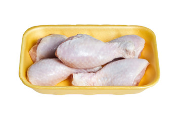 Uncooked chicken legs with skin in a yellow plastic container. Fresh poultry meat in a tray, isolated on white background
