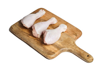 Chicken legs with skin lying on a wooden cutting board. Poultry meat isolated on white background