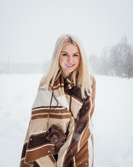 Fototapeta na wymiar Beautiful blonde girl with a vintage camera smiling against the backdrop of a winter landscape