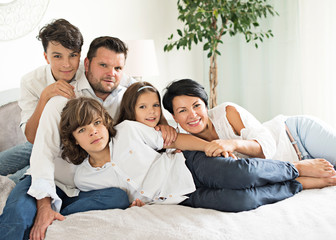  happy family with two children lying down and looking at camera - portrait  - obrazy, fototapety, plakaty