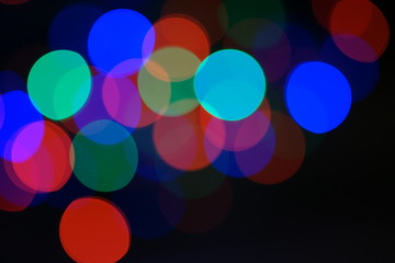 Multi-color blue holiday garland. Garland is blurred. Many big colorful round lights. Fully defocused photo. Blurred background and foreground. Holiday mood. New Year and Christmas is coming.