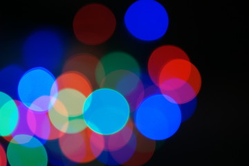 Multi-color blue holiday garland. Garland is blurred. Many big colorful round lights. Fully defocused photo. Blurred background and foreground. Holiday mood. New Year and Christmas is coming.