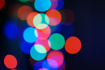 Multi-color blue holiday garland. Garland is blurred. Many big colorful round lights. Fully defocused photo. Blurred background and foreground. Holiday mood. New Year and Christmas is coming.