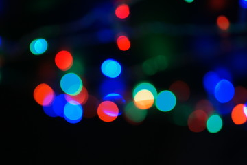 Fototapeta premium Multi-color blue holiday garland. Garland is blurred. Many big colorful round lights. Fully defocused photo. Blurred background and foreground. Holiday mood. New Year and Christmas is coming.