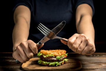 Healthy lifestyle, proper nutrition. Female hands show ban on wholesome rice burger with vegetables, herbs and cutlet on a wooden board