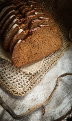 Fresh rye sliced bread on natural linen napkin on rustic wooden background