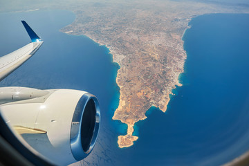 plane is flying over the island of Cyprus. Airplane wing in flight from window.