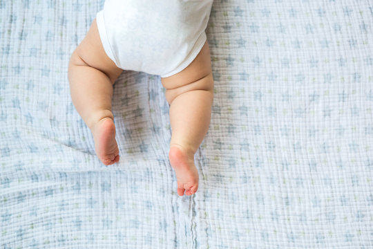 Baby wearing a onesie crawls across blanket