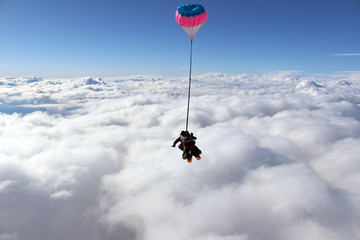 Tandem skydiving above white clouds. Extreme sport