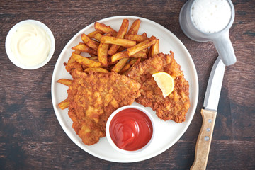 Original Wiener Schnitzel mit Maß Bier und Jagd Messer auf dem Oktoberfest Biergarten top view closeup 