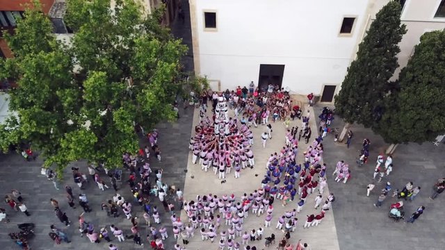 incredible upper view people in traditional dress train to make human castle on square among old houses in Tarragona
