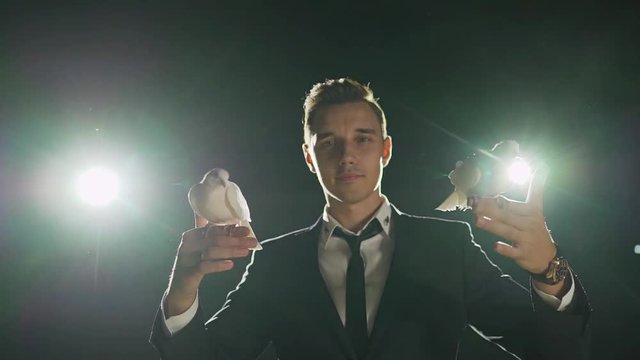 Male magician with white pigeon on dark background