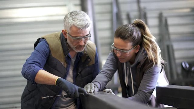 Metalworker with apprentice in workshop