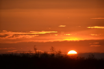 Naklejka premium Beautiful orange sunset with sun on horizon of dark landscape