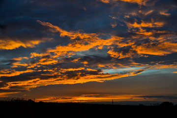 Beautiful orange clouds reflecting sunset colors above dark landscape