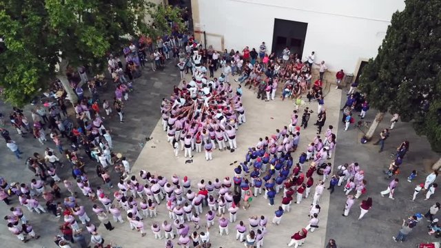 beautiful upper view spectators watch people climbing down from human pyramid at training session in Tarragona