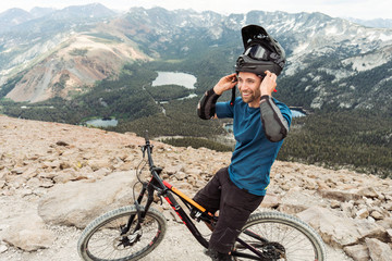 High angle view of happy man with bicycle wearing helmet on mountain