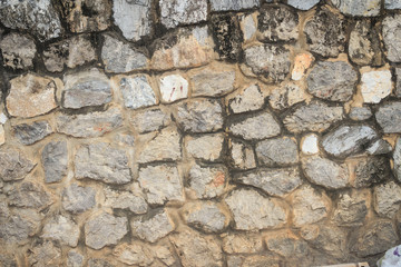 Rock wall seamless texture for background. Decorative uneven cracked real stone wall surface with cement. Grungy stone wall background