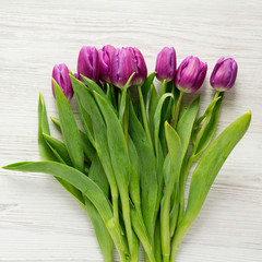 Purple tulips on white wooden surface, top view. Flat lay, overhead, from above. Close-up.