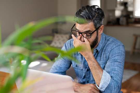 High angle view of stressed businessman with laptop computer sitting at home