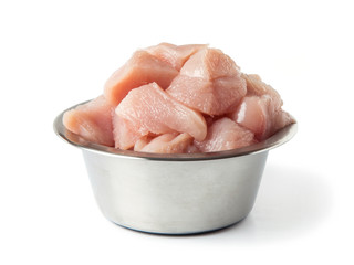 Fresh, raw pet food. Pieces of chicken fillet in a metal bowl, isolated on a white background. 