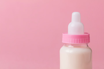 Baby bottle full of milk on a pink background