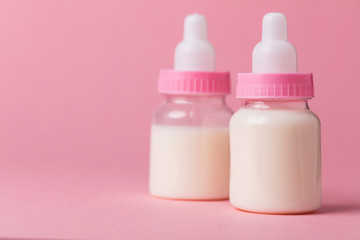 Baby bottle full of milk on a pink background