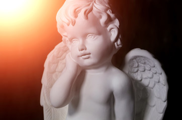 Beautiful white angel on black background close-up with flare