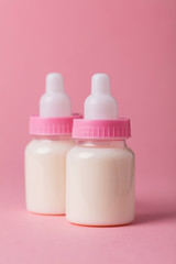 Baby bottle full of milk on a pink background