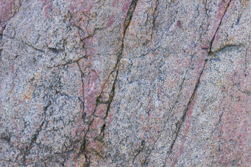 Texture of granite close up. Granite rock with reddish color. Background from solid stone. Pattern with natural material
