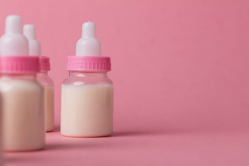 Baby bottle full of milk on a pink background