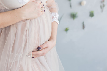 the pregnant woman keeps her hands on her stomach. pregnant woman in a dressing gown made of tulle. pregnant belly