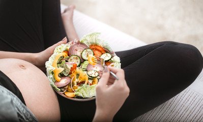 Young pregnant woman eating vegetable salad