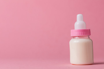 Baby bottle full of milk on a pink background