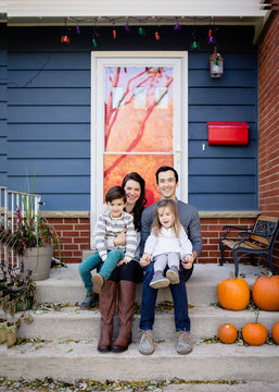 Portrait of smiling family sitting on steps against house during Halloween