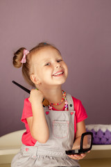 happy beautiful girl 3-4 years old sitting on the dresser with makeup laughing 