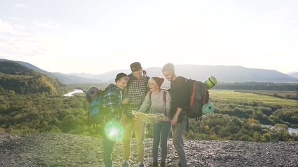 A caucasian hipsters friends using a map try to find the right way to the next destination, laughing and talking. Active lifestyle and travel concept