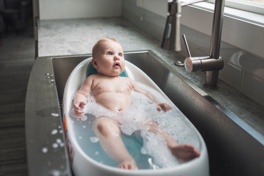 Baby boy lying in bathtub at home