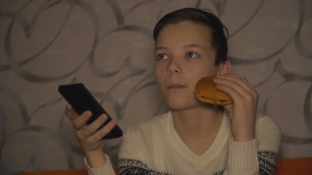 teenager watching television and eating fast food